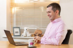 A business image of a man working his laptop in a brightly lit, modern room