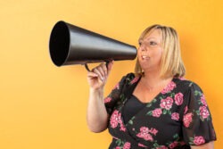 A business image of a woman using a megaphone in front of a bright yellow background