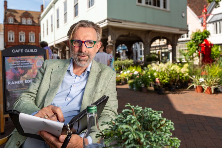 A businessman taking notes during a meeting in Faversham town centre, with Guildhall in the background