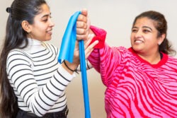 A female physiotherapist demonstrating use of a tension band to a female patient
