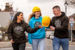 Team of three people shown talking in animated fashion as they walk along the street