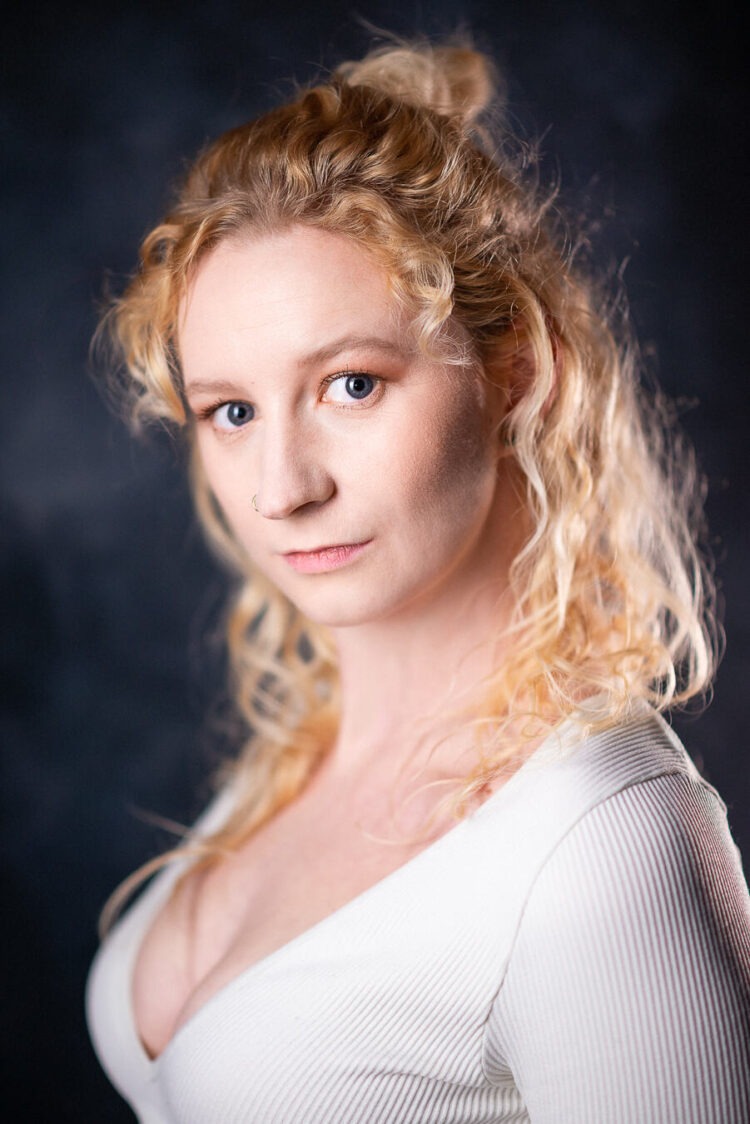 Blonde woman in white top looking at camera