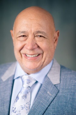 Headshot of bald man in suit smiling at a camera