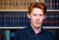 Corporate headshot of red-haired man looking at the camera