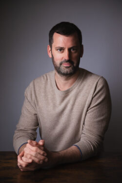 Portrait of man in white jumper looking at the camera