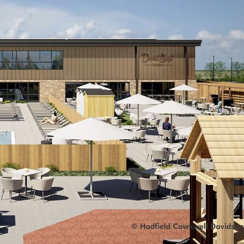 Outdoor café terrace with tables, chairs, and white umbrellas beside a modern timber‑clad building, with people seated and a rectangular pool visible on the left