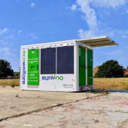 Portable solar-powered euroloo ecowelfare cabin equipped with rooftop solar panels, situated on a remote site under a clear blue sky.