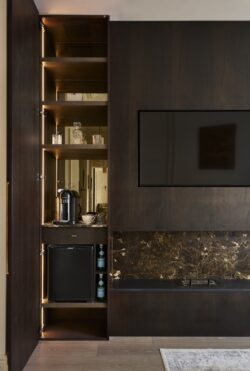Bespoke fitted cabinetry with illuminated oak shelving and dark painted cupboards, manufactured by Collins Bespoke for a London home.
